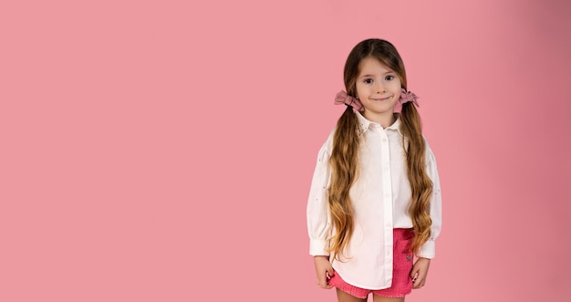 Photo happy child girl in casual white shirt isolated on pastel pink background with space for text having