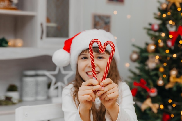 Happy child girl is holding Christmas candy canes. Happy little girl happy on the eve of Christmas. Full of hopes child. New Years Eve.