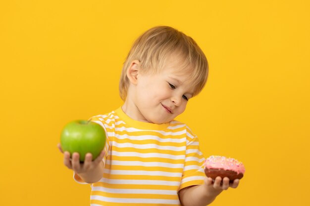 Happy child holding donut and apple