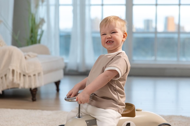 Happy child at home little toddler boy driving big vintage toy car and having fun smiling kid playin