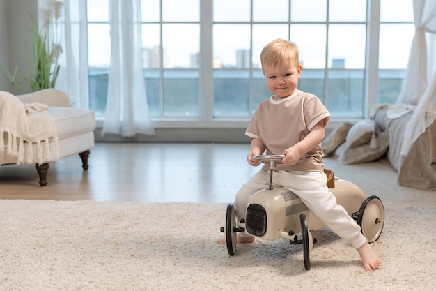 Happy child at home little toddler boy driving big vintage toy car and having fun smiling kid playin