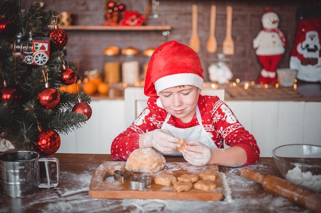 Happy child is preparing festive Christmas cookies in the kitchen of the house on Christmas eve merry Christmas and merry New year family holidays