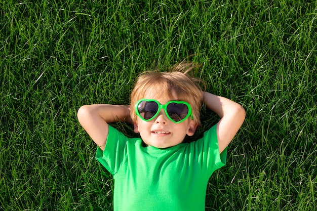 Happy child laying on green grass