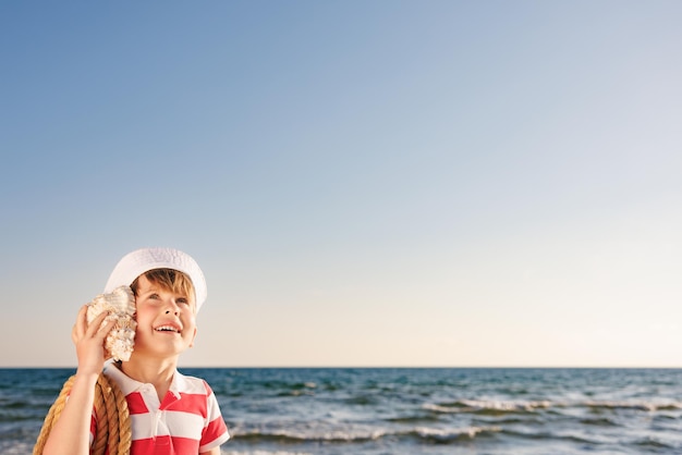 Happy child listen seashell on the beach