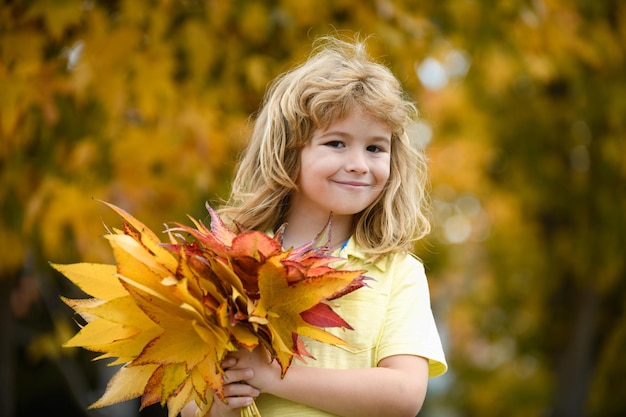 Happy child playing in the autumn park on the nature walk outdoors