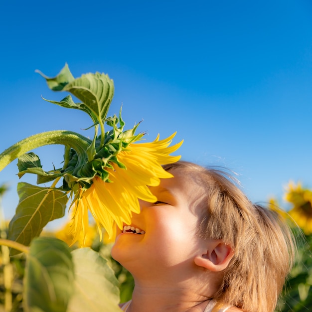 Happy child playing with sunflower outdoor