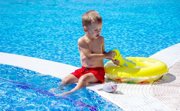 Happy child in the pool playing with a water gun.