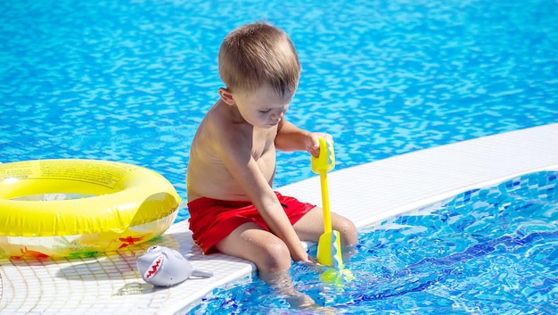 Happy child in the pool playing with a water gun.