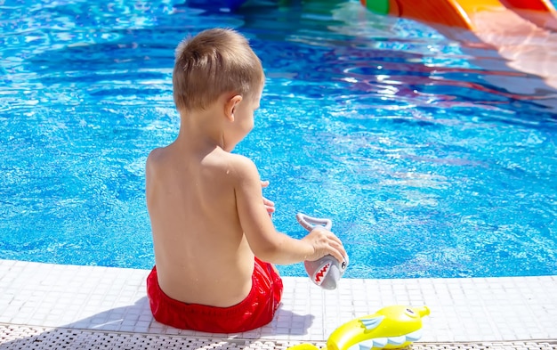 Happy child in the pool playing with a water gun.