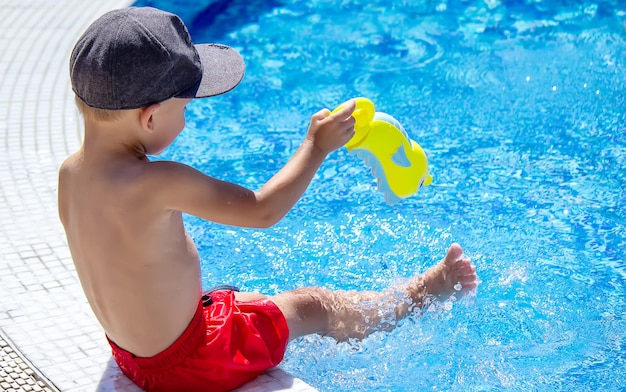 Happy child in the pool playing with a water gun.