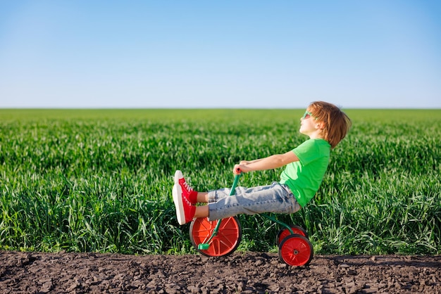 Happy child riding bike outdoor in spring green field