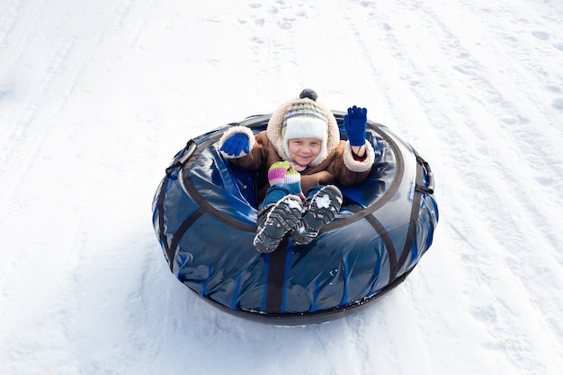 Happy child sitting in a tube and waving hand