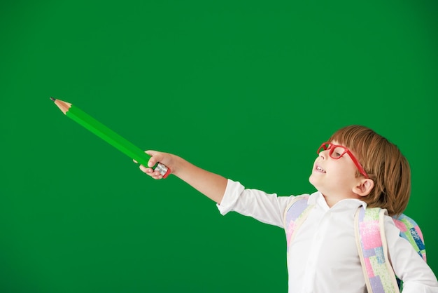 Happy child student against green chalkboard