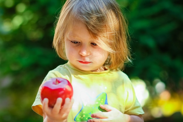 Happy child with apple on nature in the garden background