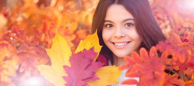 Happy child with autumn colorful leaves at rowan tree portrait Autumn fall child for poster design Banner header copy space