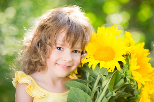 Happy child with bouquet of flowers against green background Spring family holiday concept Mothers day