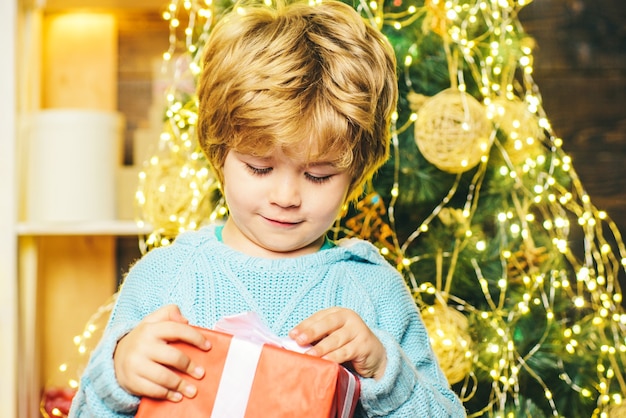 Happy child with Christmas gift. Portrait of Santa kid with gift looking at camera. Kid having fun