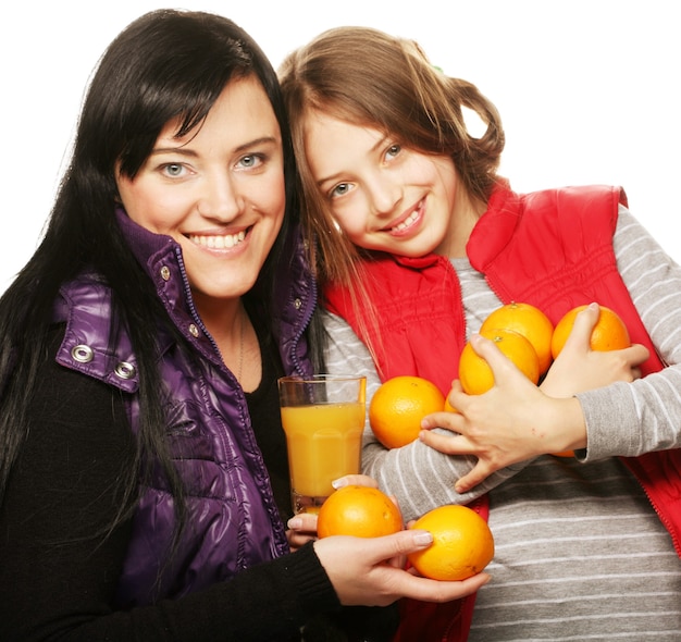 Happy child with mother holding oranges and juice