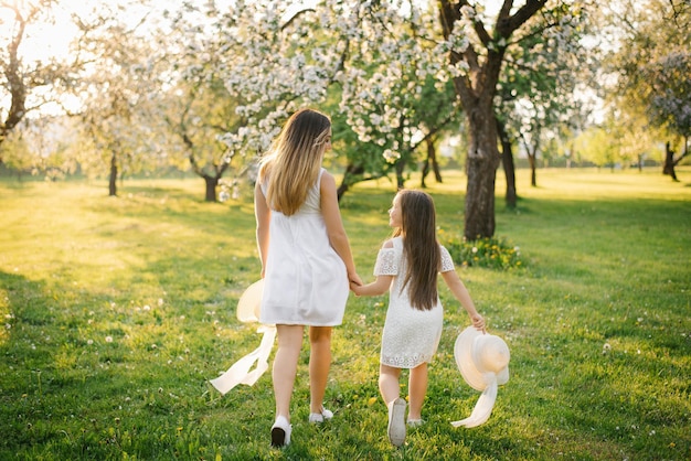 Happy childhood with mom the daughter holds her mother's hand and runs with her through