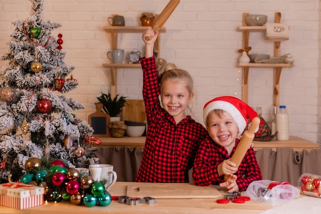 Happy children bake Christmas cookies at home in the kitchen