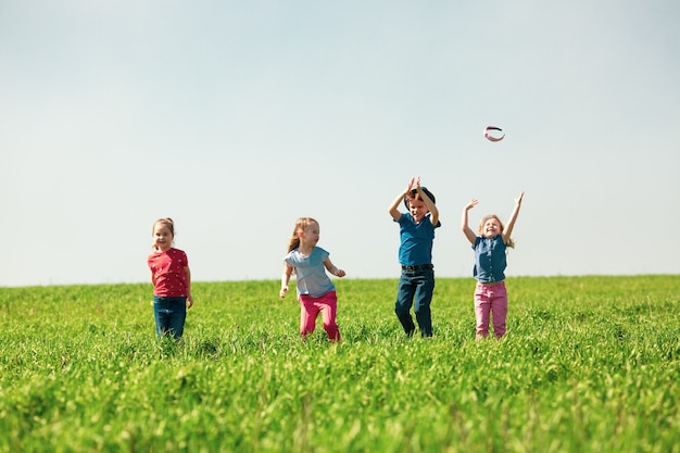 Happy children of boys and girls run in the park on the grass on a sunny summer day 