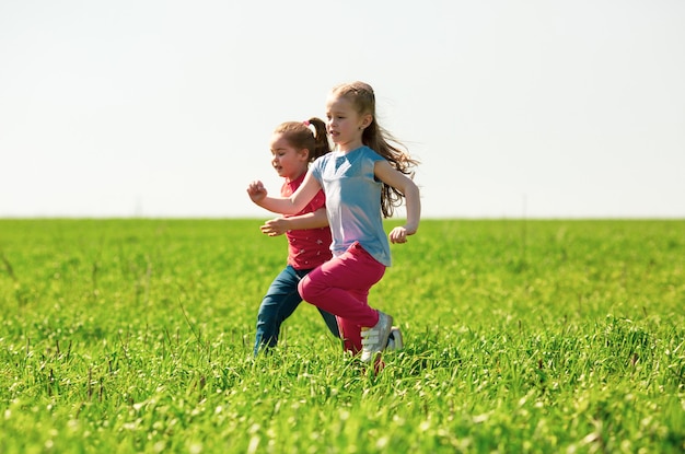 Happy children of boys and girls run in the park on the grass on a sunny summer day