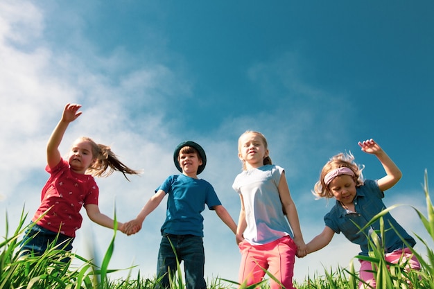 Happy children of boys and girls run in the park on the grass on a sunny summer day