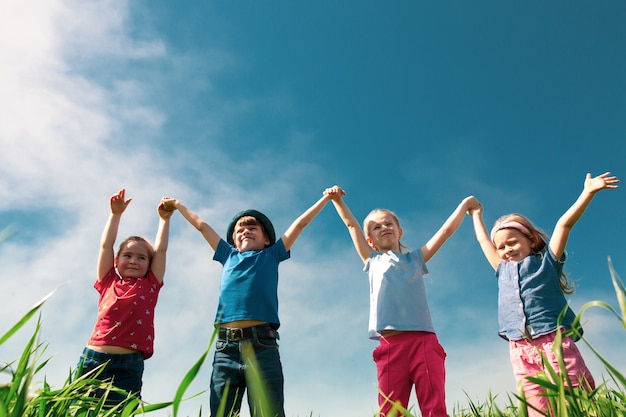 Happy children of boys and girls run in the park on the grass on a sunny summer day