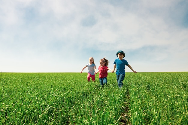 Happy children of boys and girls run in the Park on the grass on a Sunny summer day 