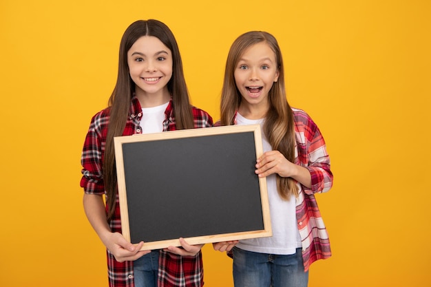 Happy children in casual checkered hold school blackboard for copy space, announcement.