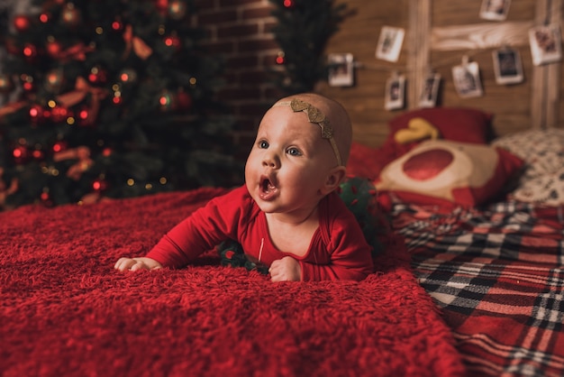 Happy children celebrating New Year and Christmas at decorated Christmas tree and garlands