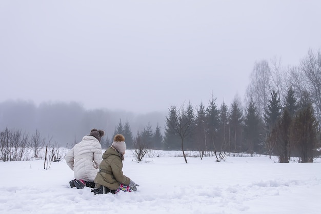 Happy children make a snowman in a snow-covered field in the countryside.