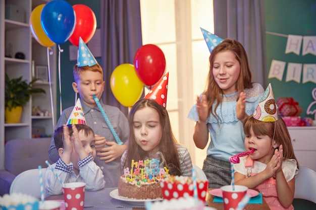 Happy children in party caps celebrating a birthday