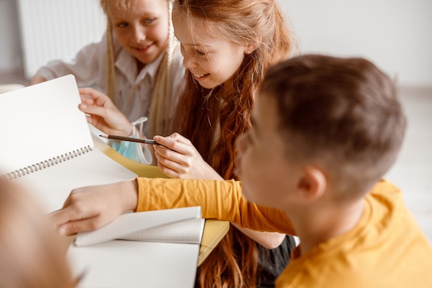 Happy children sitting at the table and using notebooks