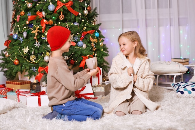 Happy children with cup as a gift in the decorated Christmas room