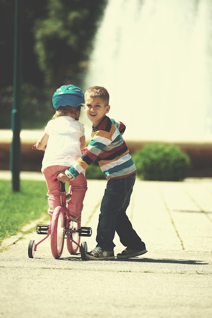 Happy childrens outdoor,  brother and sister in park have fun. Boy and girl in park learning to ride a bike.