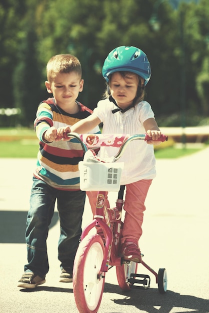 Happy childrens outdoor,  brother and sister in park have fun. Boy and girl in park learning to ride a bike.