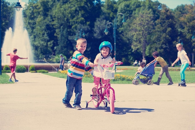 Happy childrens outdoor,  brother and sister in park have fun. Boy and girl in park learning to ride a bike.