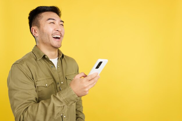 Happy chinese man laughing while using the mobile