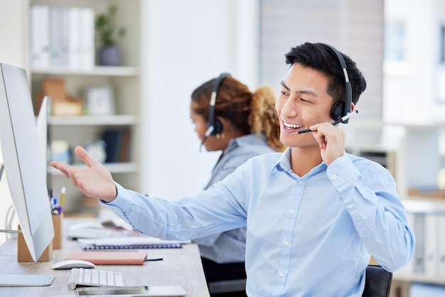 Happy confident and helpful call centre agent talking on a headset while working on computer in an office Salesman or consultant operating a help desk for customer care and service support