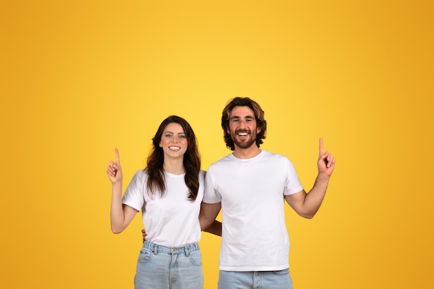 Happy and confident man and woman pointing upwards showing positivity and having a good time