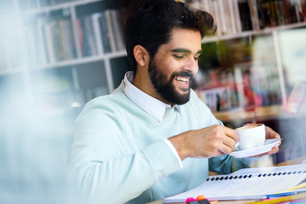 Happy confident young man working, studying and having a coffee break