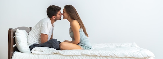 The happy couple on the bed kissing on the white background