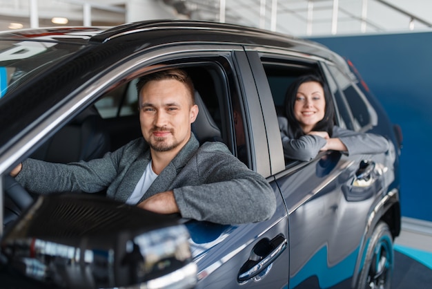 Happy couple buying new car in showroom, departure from the salon.