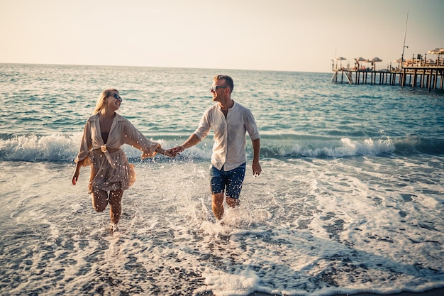 Happy couple by the sea Honeymoon lovers Man and woman on the island Beautiful couple having fun on the seashore Happy couple on vacation Man and woman by the sea