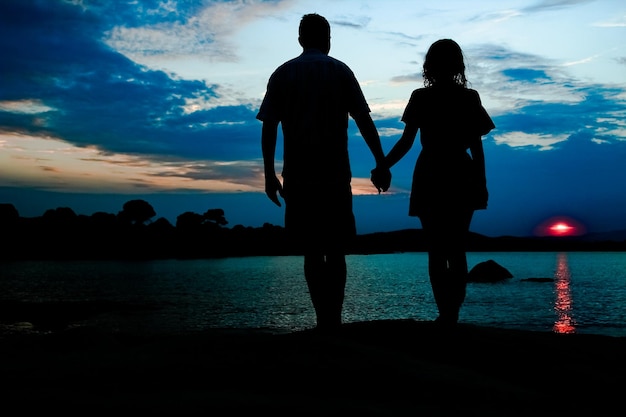 Happy couple by the sea on nature silhouette background