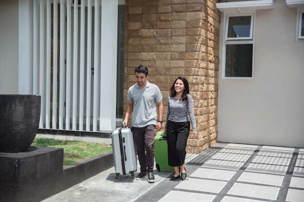 Happy couple carrying their suitcase