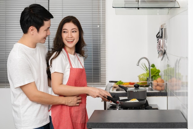 Happy couple cooking and preparing food in the kitchen at home man in hugging woman