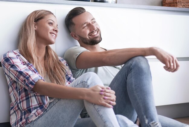 Happy couple discussing something sitting on the kitchen floor