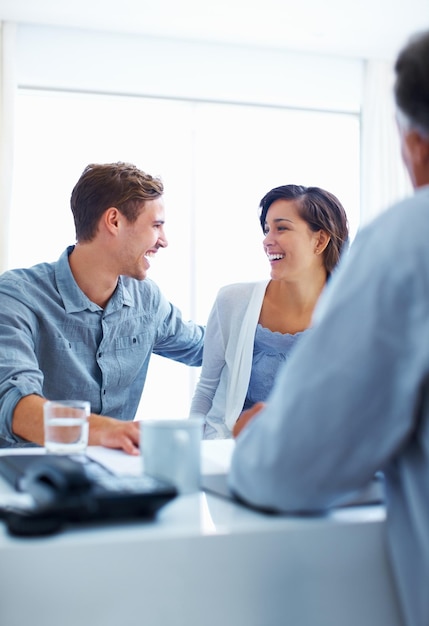 Happy couple discussing with advisor Portrait of happy couple laughing while discussing with financial advisor